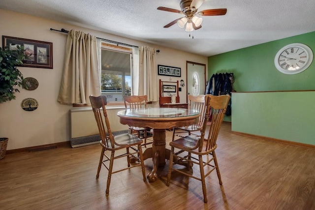 dining space with light hardwood / wood-style flooring, a textured ceiling, and ceiling fan