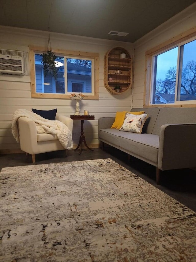 living area featuring an inviting chandelier, wood walls, and a wall mounted AC