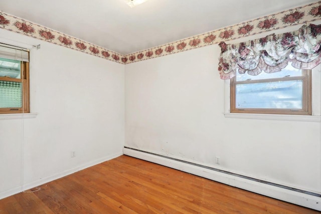 empty room featuring hardwood / wood-style flooring and a baseboard radiator