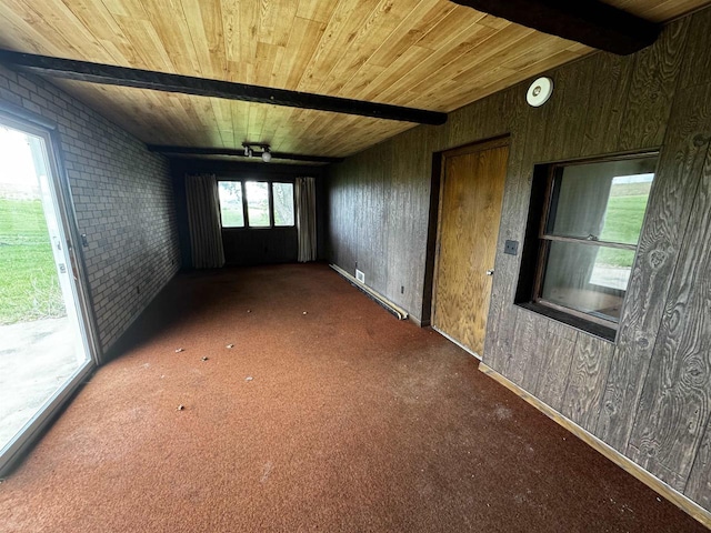 empty room featuring a wealth of natural light, brick wall, wooden ceiling, and wood walls