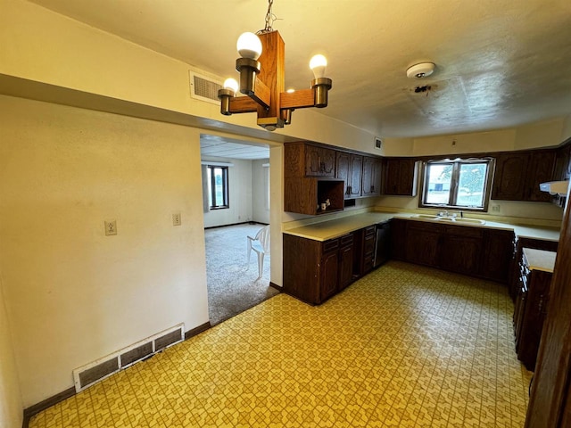 kitchen featuring dark brown cabinets, hanging light fixtures, light carpet, range hood, and an inviting chandelier