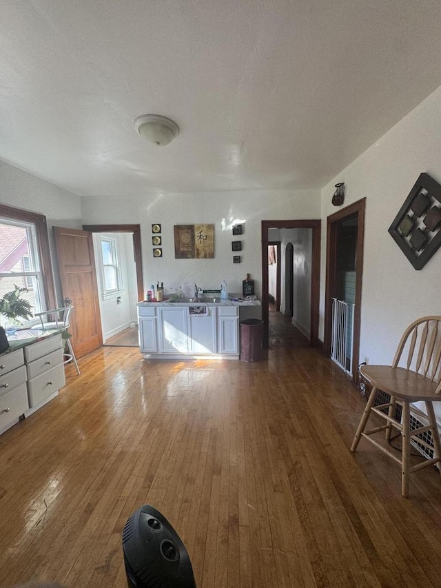 kitchen featuring hardwood / wood-style floors, stainless steel dishwasher, white cabinets, and arched walkways