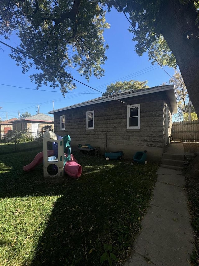 view of side of home with a lawn and a playground