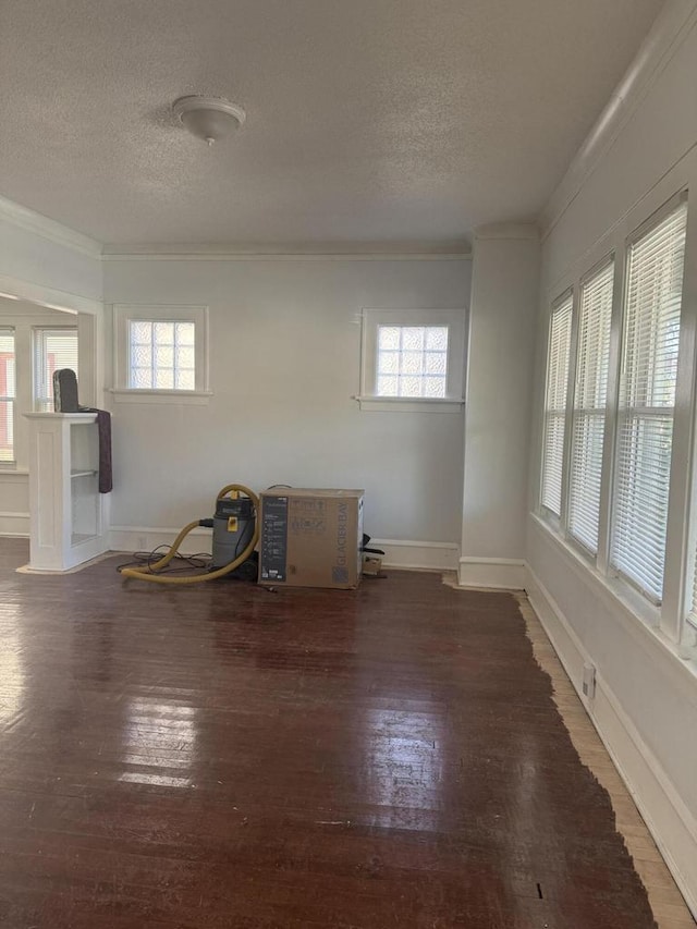 unfurnished room with baseboards, crown molding, a textured ceiling, and hardwood / wood-style floors