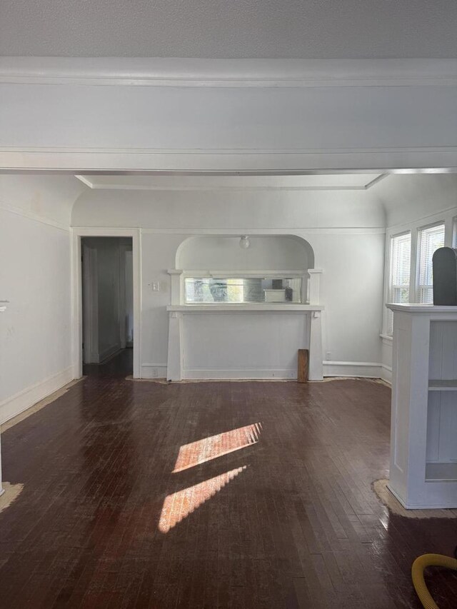 unfurnished living room with baseboards, ornamental molding, and hardwood / wood-style floors