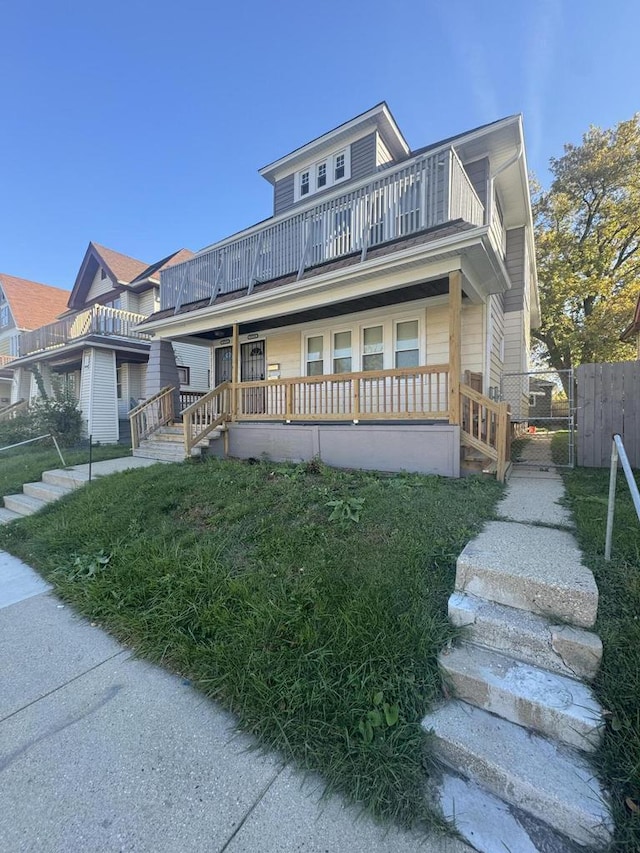 view of front of home with a gate, fence, a balcony, and stairway