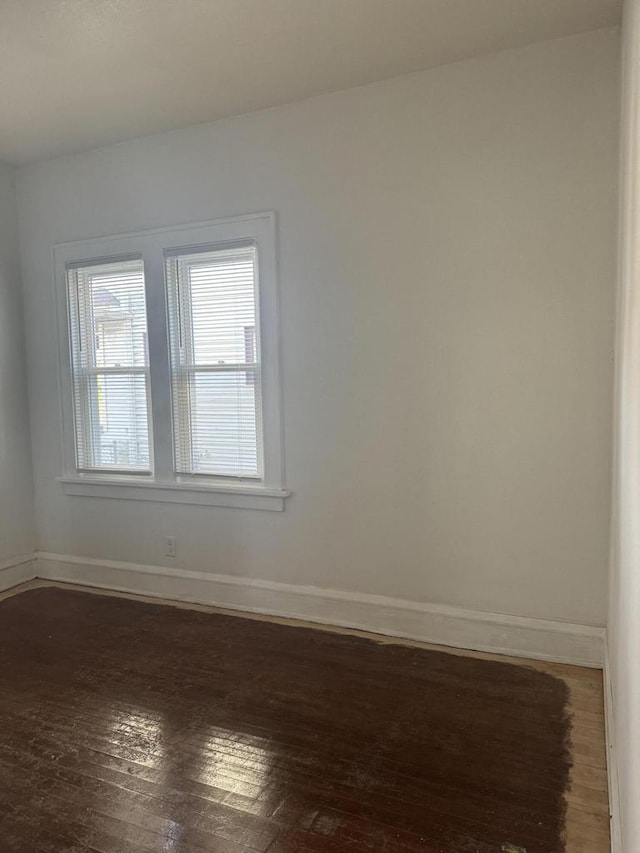spare room featuring baseboards and dark wood-style floors