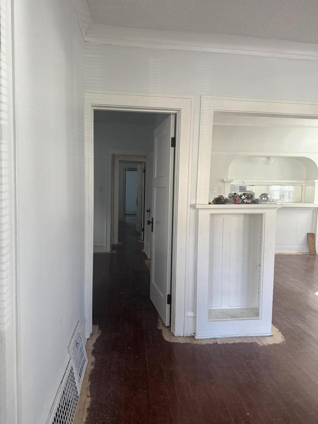 hallway featuring hardwood / wood-style flooring, ornamental molding, and visible vents