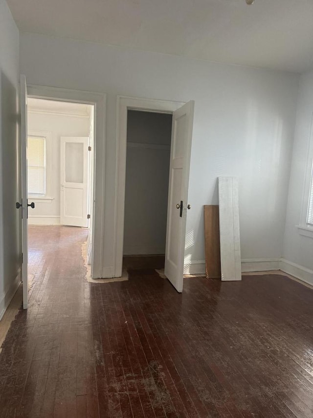 unfurnished bedroom featuring baseboards, a closet, and hardwood / wood-style flooring