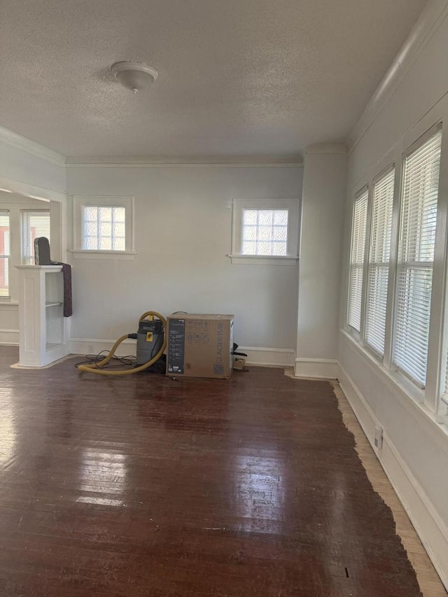 empty room with ornamental molding, dark wood-type flooring, and plenty of natural light