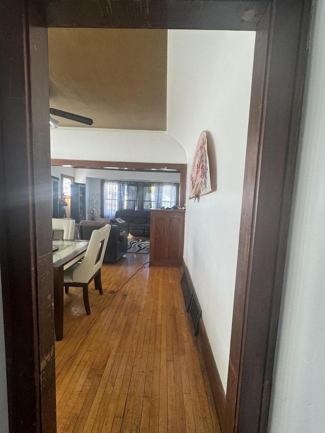 hallway with baseboards, hardwood / wood-style flooring, and visible vents