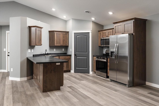 kitchen with kitchen peninsula, sink, vaulted ceiling, light wood-type flooring, and appliances with stainless steel finishes