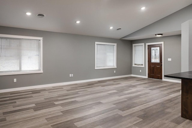 unfurnished living room featuring vaulted ceiling and light wood-type flooring