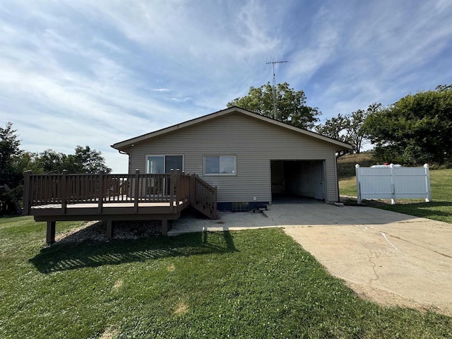 rear view of house featuring a wooden deck, a garage, and a lawn