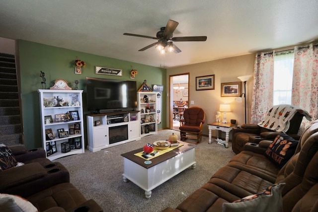 carpeted living room featuring a fireplace and ceiling fan