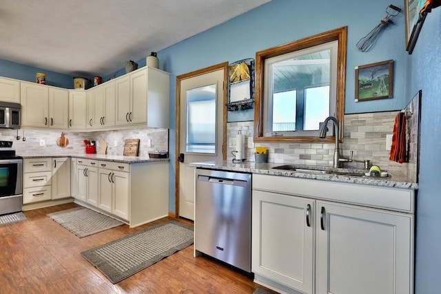 kitchen featuring backsplash, sink, stainless steel appliances, and light wood-type flooring