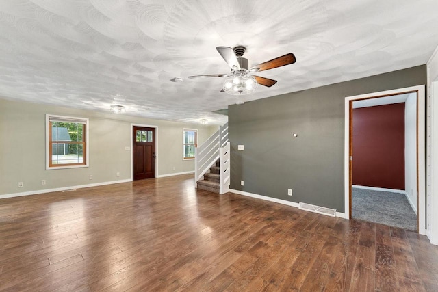 unfurnished living room with a textured ceiling, ceiling fan, and dark hardwood / wood-style flooring