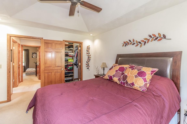 bedroom with a closet, a spacious closet, vaulted ceiling, light colored carpet, and ceiling fan