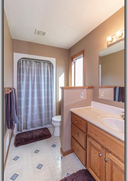 bathroom featuring vanity, toilet, and tile patterned flooring