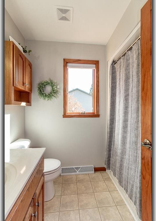 bathroom with vanity, curtained shower, toilet, and tile patterned floors