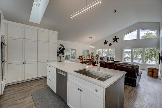 kitchen featuring wood-type flooring, vaulted ceiling with skylight, a wealth of natural light, and a kitchen island with sink