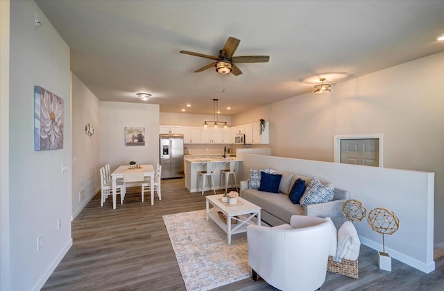 living room with sink, dark wood-type flooring, and ceiling fan