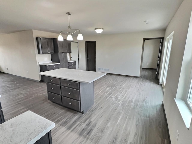 kitchen featuring decorative light fixtures, wood-type flooring, a notable chandelier, and a center island