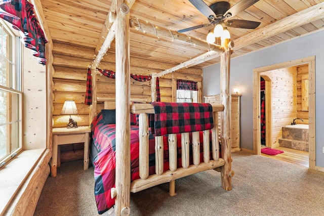 bedroom featuring beam ceiling, wooden ceiling, carpet, rustic walls, and ceiling fan