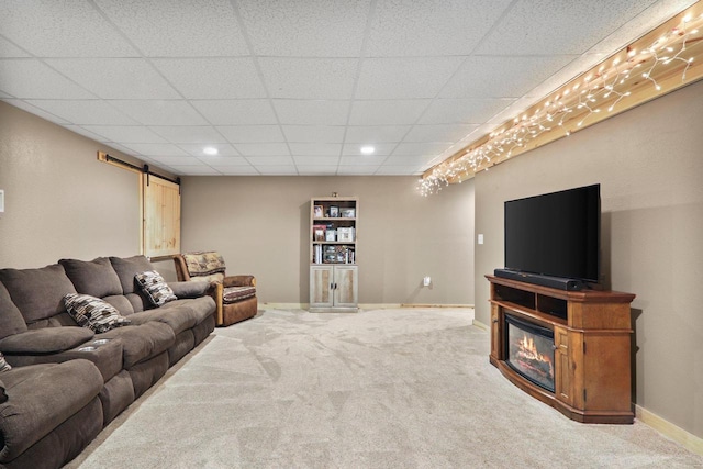 living room featuring carpet, a drop ceiling, and a barn door