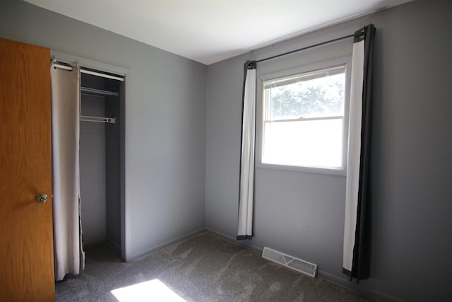 unfurnished bedroom with dark carpet and a closet