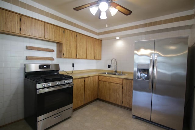 kitchen featuring ceiling fan, stainless steel appliances, tile walls, and sink