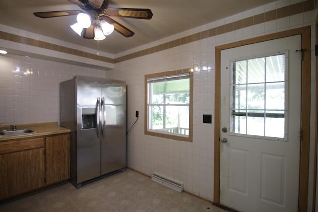 kitchen with a wealth of natural light, tile walls, stainless steel fridge, and sink