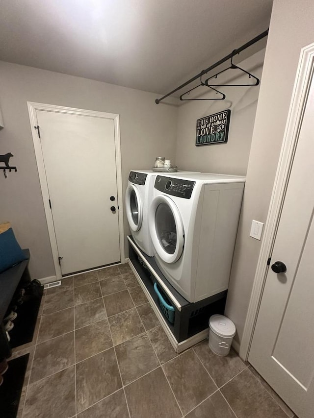 washroom with dark tile patterned floors and washer and clothes dryer