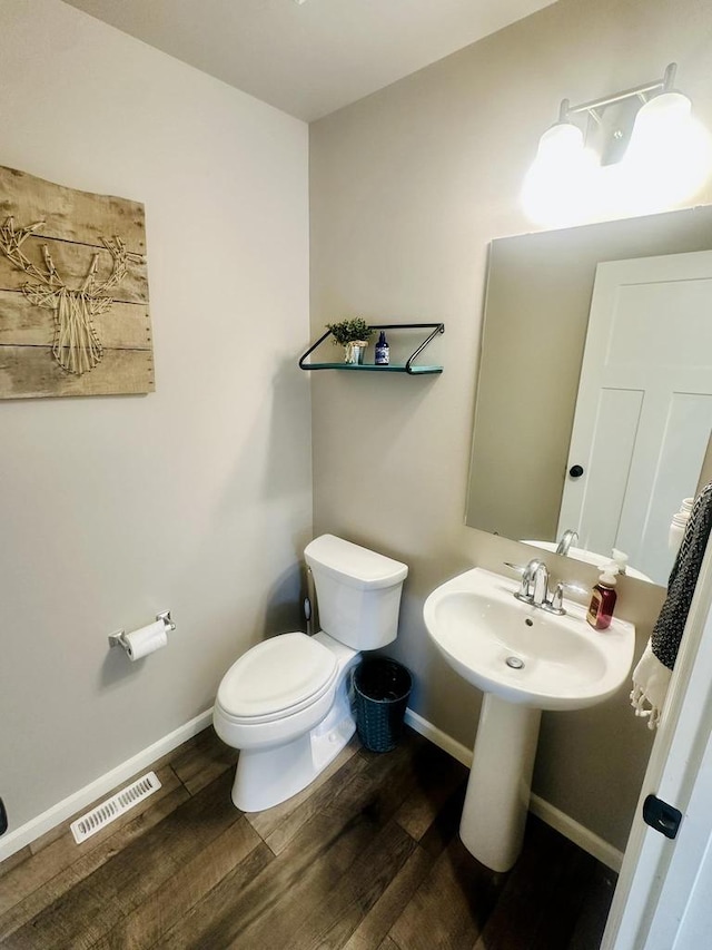 bathroom with toilet, wood-type flooring, and sink