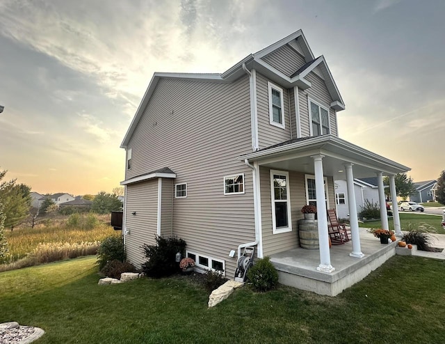 property exterior at dusk with a lawn and a porch