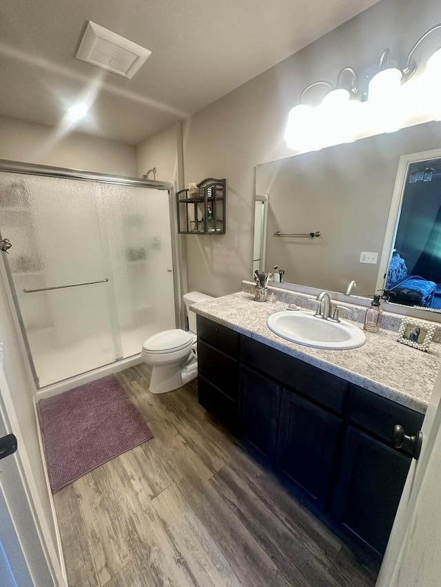 bathroom with vanity, toilet, hardwood / wood-style flooring, and a shower with door