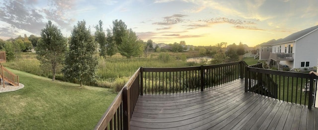 deck at dusk featuring a lawn