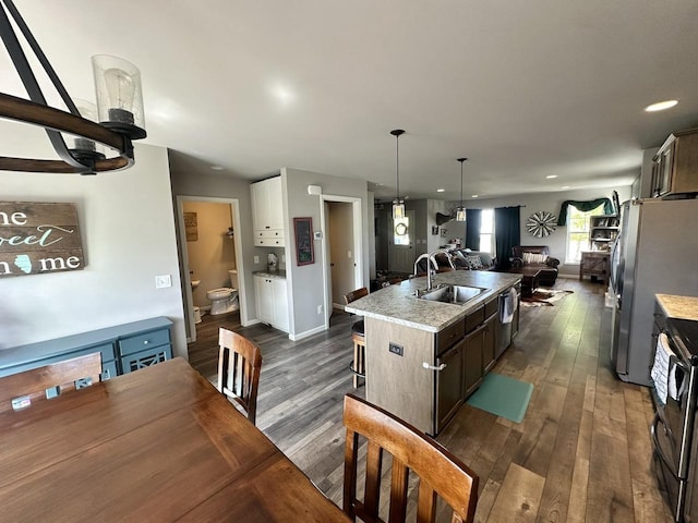 kitchen featuring a center island with sink, dark hardwood / wood-style floors, stainless steel appliances, dark brown cabinetry, and sink