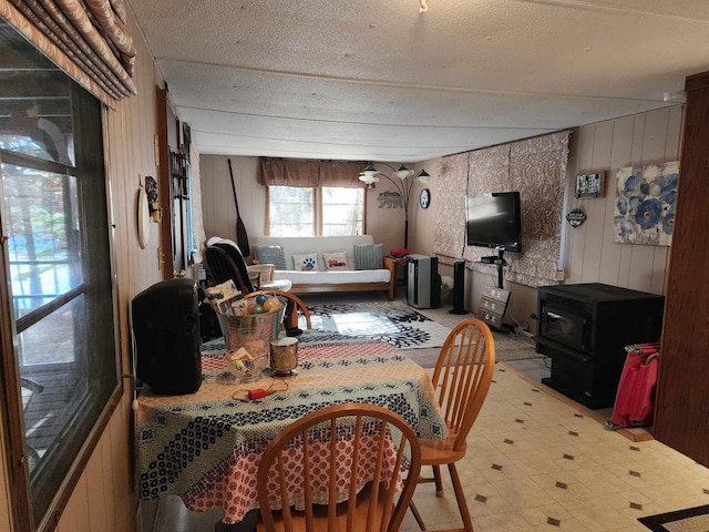 dining space with wooden walls and a wood stove