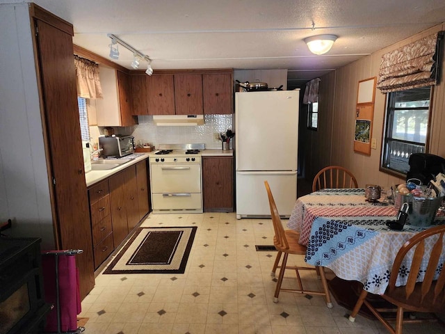 kitchen with white appliances, wood walls, decorative backsplash, and sink