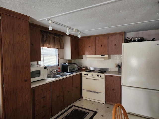 kitchen with sink, a textured ceiling, and white appliances