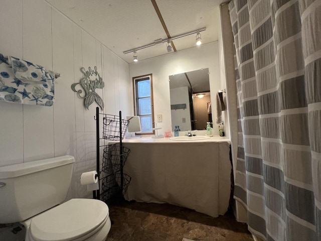 bathroom with toilet, a shower with curtain, rail lighting, vanity, and a textured ceiling