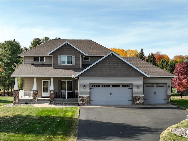 craftsman house featuring covered porch, a garage, and a front lawn