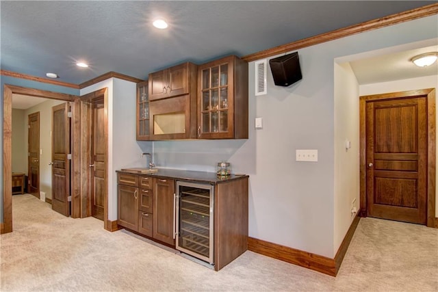 bar featuring wine cooler, ornamental molding, sink, and light carpet