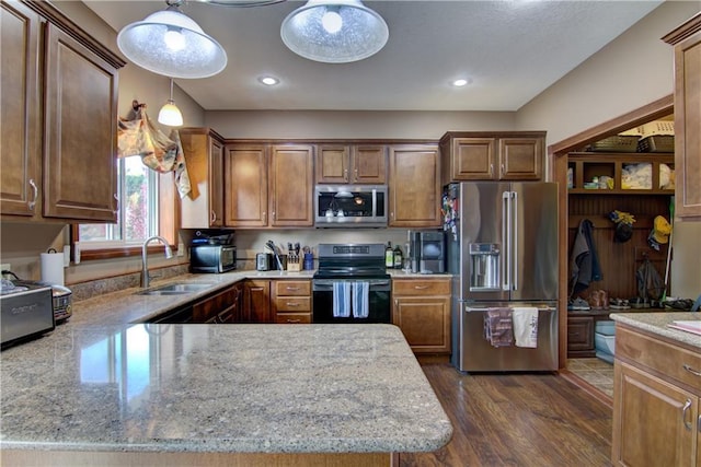 kitchen featuring dark hardwood / wood-style flooring, appliances with stainless steel finishes, sink, pendant lighting, and light stone counters