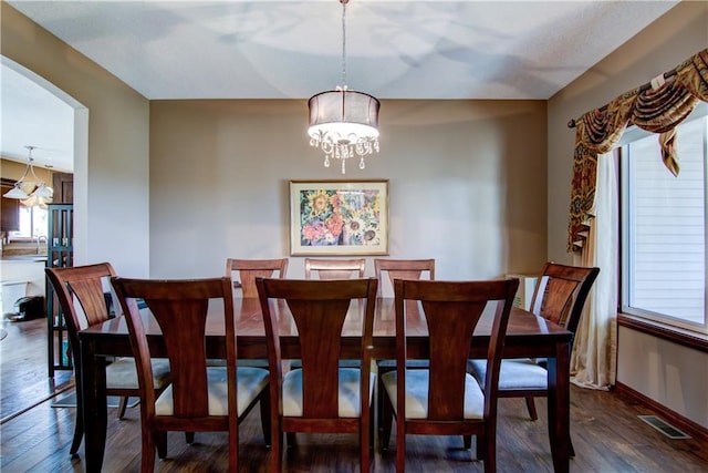 dining space with a notable chandelier and dark hardwood / wood-style flooring