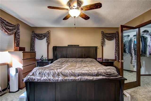 bedroom featuring a closet, a textured ceiling, light colored carpet, and ceiling fan