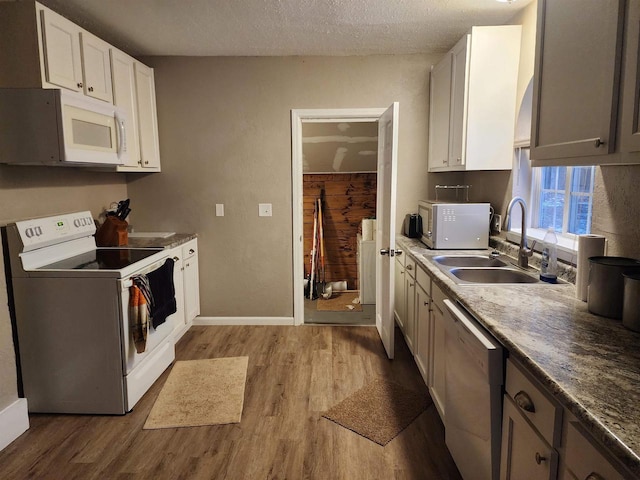 kitchen with a textured ceiling, white appliances, sink, white cabinets, and light hardwood / wood-style floors