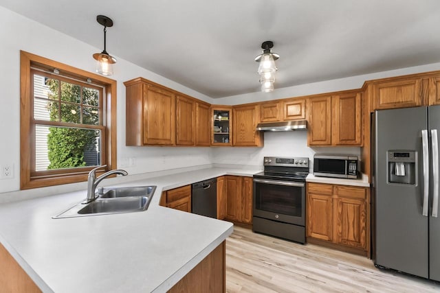 kitchen with kitchen peninsula, appliances with stainless steel finishes, pendant lighting, light hardwood / wood-style floors, and sink