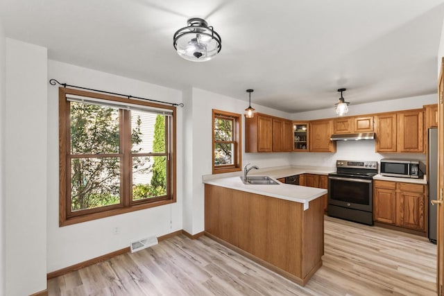 kitchen with kitchen peninsula, appliances with stainless steel finishes, light hardwood / wood-style flooring, sink, and decorative light fixtures